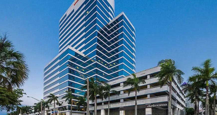 Modern glass office building with palm trees at dusk