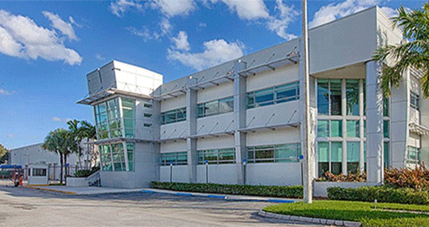 MIAMI-INT Modern commercial building with large glass windows and white exterior
