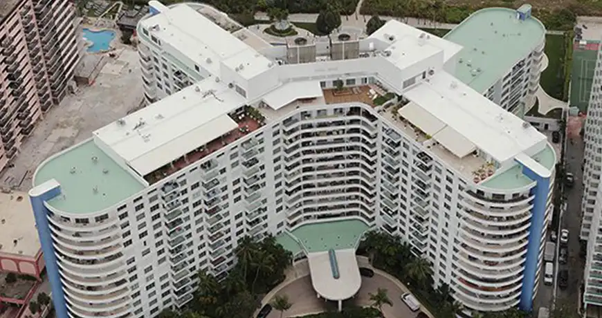 a curved high-rise building with a white rooftop and balconies