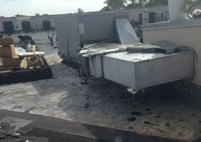 Damaged commercial rooftop with HVAC units and construction debris in Miami