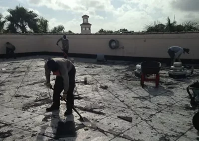 Workers removing debris from a damaged commercial roof in Miami
