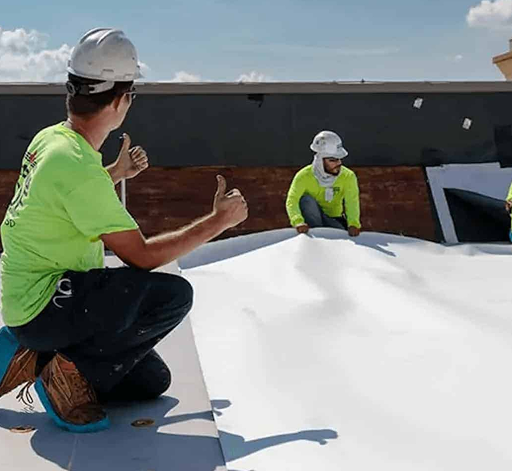 image - 2025-04-17T180158.746 Contractors laying down white TPO roofing membrane on commercial roof.