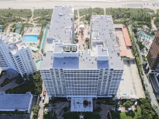 Aerial view of Balmoral Condominium high-rise with a new white modified bitumen roof among oceanfront towers in Florida