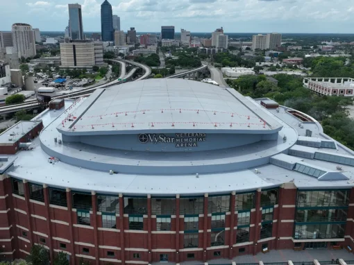 Aerial view of Vystar Veterans Memorial Arena in Jacksonville, FL with its restored white silicone-coated roof and the downtown skyline