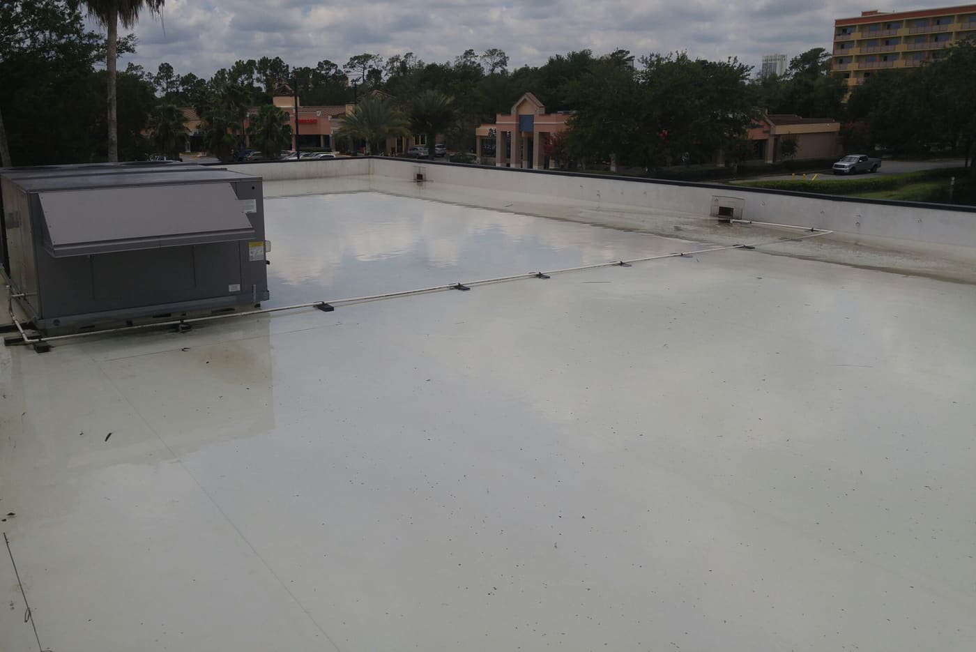 Standing water across a Florida commercial roof around a rooftop HVAC unit after the drains clogged